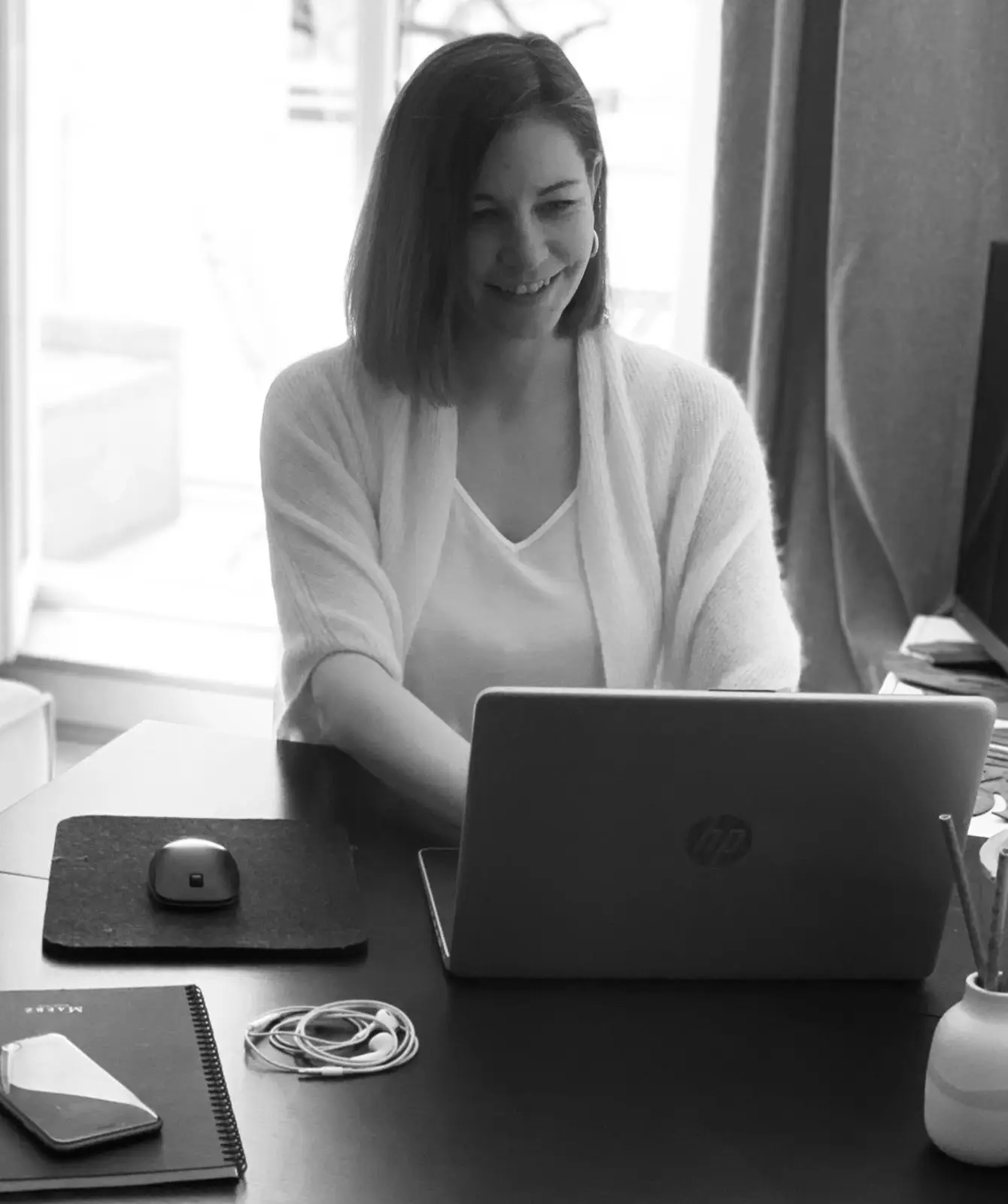 Julia, Website-Mentorin, sitzt am Schreibtisch und schaut freudig in ihren Laptop. Als Website-Managerin hat sie unzählige Webseiten selbst erstellt.